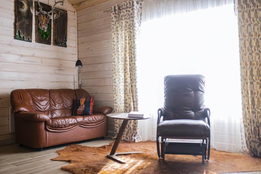 В гостевом доме Живица в зоне отдыха комфортный двухместный диван и кожаное кресло - качалка